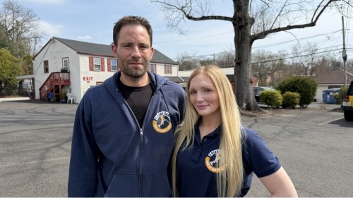 Two staff members standing outside a building in a parking lot on a clear day